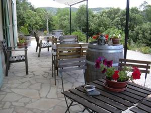a patio with wooden tables and benches and flowers at Chambres d'Hôtes Le Cadran Solaire in Cabrières