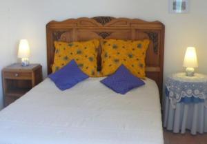 um quarto com uma cama com almofadas azuis e duas mesas em Chambres d'Hôtes Le Cadran Solaire em Cabrières