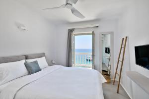 a bedroom with a bed and a view of the ocean at Tourlos Bay Villas Mykonos in Tourlos