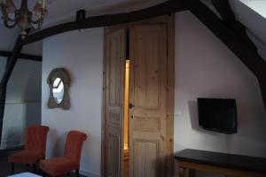 um quarto com a porta aberta, com uma televisão e duas cadeiras em Logis La Ferme Du Vert em Wierre-Effroy