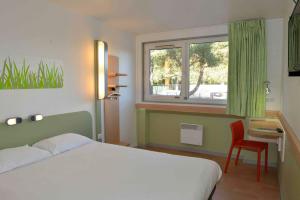 a bedroom with a bed and a window and a chair at ibis budget Bordeaux Lac in Bordeaux +46 photos