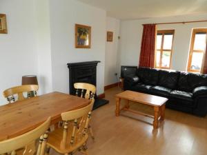 a living room with a wooden table and a black couch at Kinsale Coastal Cottages in Garrylucas