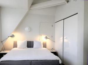 a bedroom with a white bed with two lamps at Urban Residences Maastricht in Maastricht