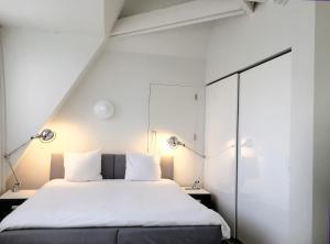 a bedroom with a white bed and white walls at Urban Residences Maastricht in Maastricht