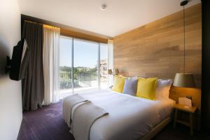 a bedroom with a large bed with a large window at Vale d'Azenha Hotel Rural & Residences in Alcobaça