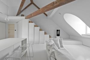 a white room with a couch and a staircase at City Entrance Apartment in Vilnius