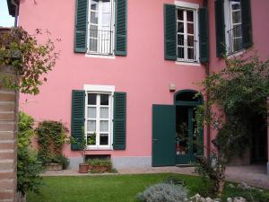 una casa rosa con persianas verdes en La Locanda del Melograno en Moncalvo