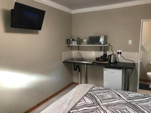 a bedroom with a bed and a desk with a tv on the wall at B@home in Bloemfontein