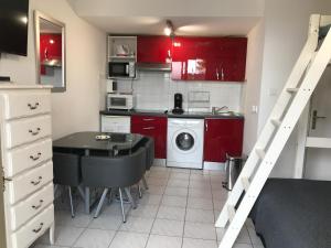 una piccola cucina con armadi rossi, tavolo e scrivania di Residence Acapulco a Villeneuve-Loubet