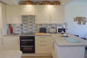 a kitchen with white cabinets and a counter top at 2 Fernleigh Villas in Perranporth