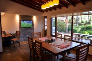 a dining room with a wooden table and a television at Cabañas del Bosque in Mar Azul