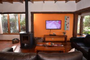 sala de estar con chimenea y TV en Cabañas del Bosque en Balneario Mar Azul