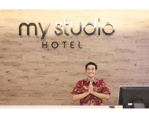 My Studio Hotels Kualanamu Airport Medan في ميدان: رجل واقف امام لافته الفندق