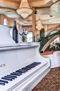 Forest Villas Hotel في بريسكوت: بيانو أبيض في غرفة مع كؤوس النبيذ