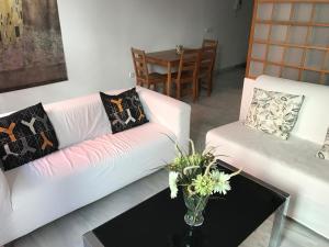 una sala de estar con 2 sofás blancos y una mesa. en Málaga Apartamentos - Jinetes, 13, en Málaga