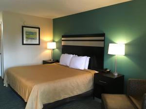 a hotel room with a bed with two lamps and a chair at GuestHouse Inn Dothan in Dothan