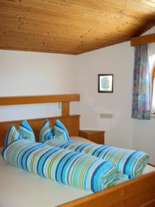 un letto con cuscini blu e gialli in una camera da letto di Haus Neururer a Kauns
