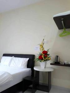 a bedroom with a bed and a table with a vase of flowers at Red Motel in Nibung Tebal