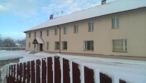 Ein schneebedecktes Gebäude neben einem Zaun in der Unterkunft Klintis in Jaungulbene