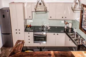 uma cozinha com armários brancos e um frigorífico de aço inoxidável em Cal Pastisser de Taús em Tahús