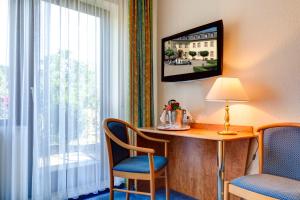 Habitación de hotel con escritorio, sillas y ventana en Der Westerwaldwirt Hotel Landhaus - Stähler, en Hemmelzen