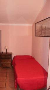 a red bed in a small room with a table at Case Danti Padronale in Santa Fiora