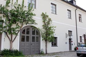 une maison blanche avec une porte grise et des arbres dans l'établissement Ultra Alpes Ludwig Suite, à Rottenbuch