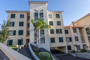 an apartment building with a palm tree in front of it at Blue Sky in Funchal