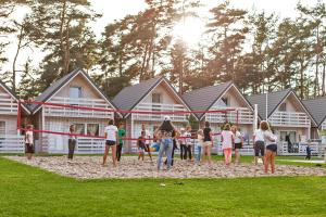 a group of people playing a game in front of houses at Holiday Park & Resort Pobierowo - całodniowe animacje i podgrzewany basen w cenie in Pobierowo