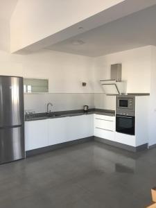 Una cocina con gabinetes blancos y electrodomésticos de acero inoxidable. en Casa Fenix, en Tinajo
