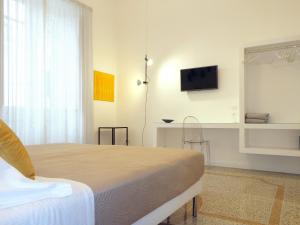um quarto com uma cama e uma televisão na parede em Re Ruggero Rooms em Reggio di Calabria