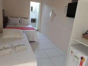 Habitación blanca con 2 camas y TV. en Pousada Vitória, en Penha