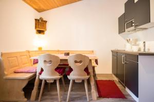 a kitchen with a table and two white chairs at Ferienwohnung "Zum Leitnerbachl" in Schliersee