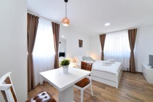 a white living room with a white table and chairs at Piccolo Apartments in Zagreb