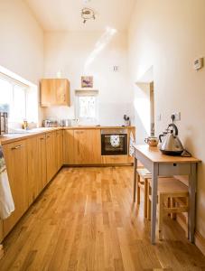 a kitchen with wooden cabinets and a table with a kettle on it at Ty'r Afon - River Cottage in Bala