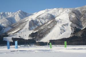 a snow covered mountain with signs in front of it at B&B Santana Hakuba in Hakuba