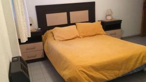 1 dormitorio con 1 cama grande con sábanas y almohadas amarillas en Hotel del Faro en Mar del Plata