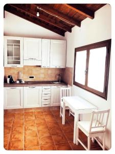 - une cuisine avec des placards blancs, une table et des chaises dans l'établissement Appartamento Angela, à Selargius