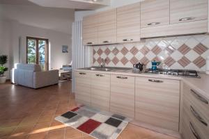 a kitchen with wooden cabinets and a living room at Villa d'aMare Capri View in Massa Lubrense
