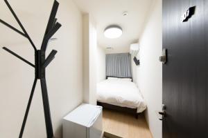 Cette petite chambre comprend un lit et une porte. dans l'établissement Rota Hostel, à Osaka