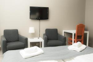 a bedroom with two chairs and a bed and a flat screen tv at Oppdal Gjestetun Hotell in Oppdal