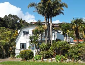 a white house with palm trees in front of it at Harbour View Bed & Breakfast in Tairua
