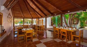 un restaurante con mesas de madera y sillas en una habitación en Hotel Fiesta, en Puerto Ayora