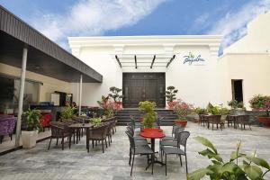 a patio with tables and chairs in front of a building at Bamboo Green Riverside Hotel in Danang