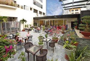 a patio with tables and chairs and potted plants at Bamboo Green Riverside Hotel in Danang