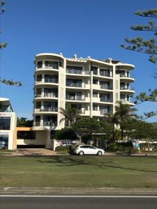 a white car parked in front of a large building at Meridian Alex Beach Apartments in Alexandra Headland