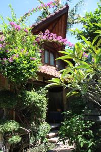 a house with pink flowers on the side of it at Blue Star Bungalows & Cafe in Amed