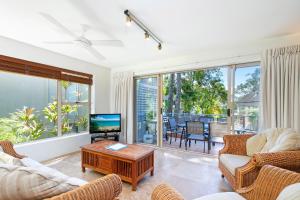 een woonkamer met banken, een televisie en een tafel bij Alderly Apartment 6, Little Cove in Noosa Heads