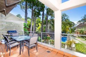 een balkon met een tafel en stoelen en uitzicht op een zwembad bij Alderly Apartment 6, Little Cove in Noosa Heads