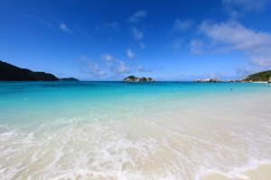 a beach with blue water and islands in the background at Kerama Terrace in Tokashiki